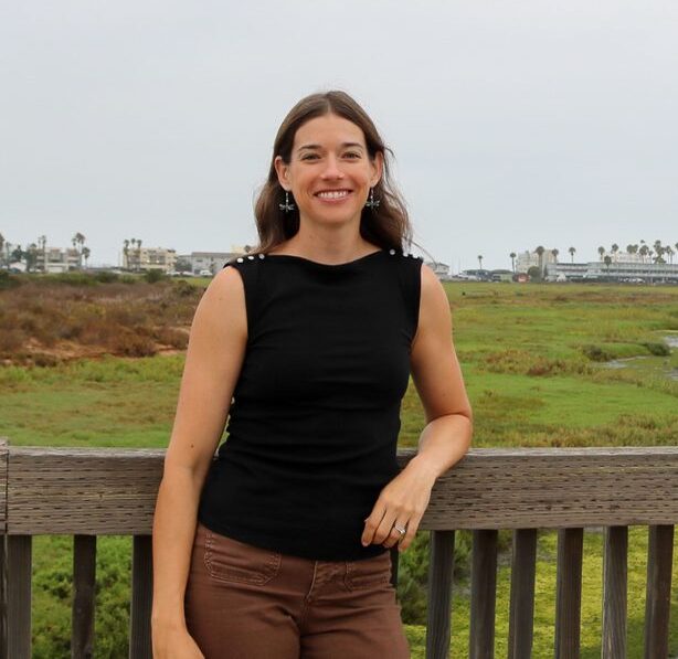 Woman smiling at Tijuana Estuary with marsh and trail in background.