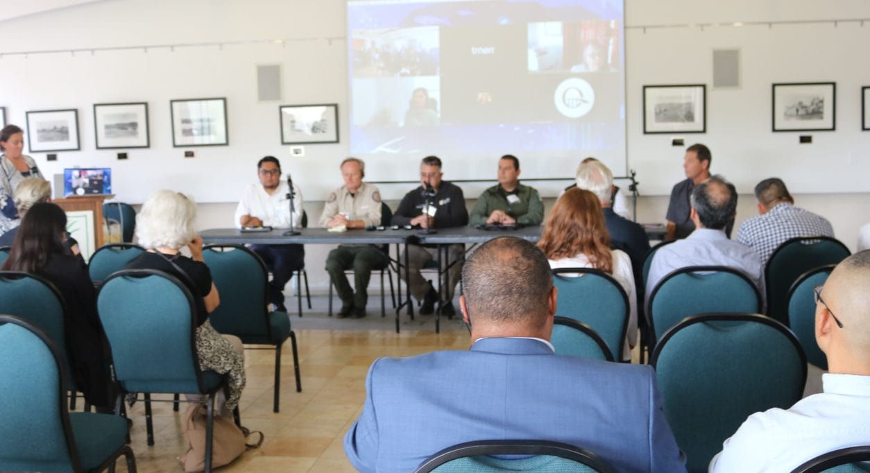 Four speaker panel in front of a room of people.