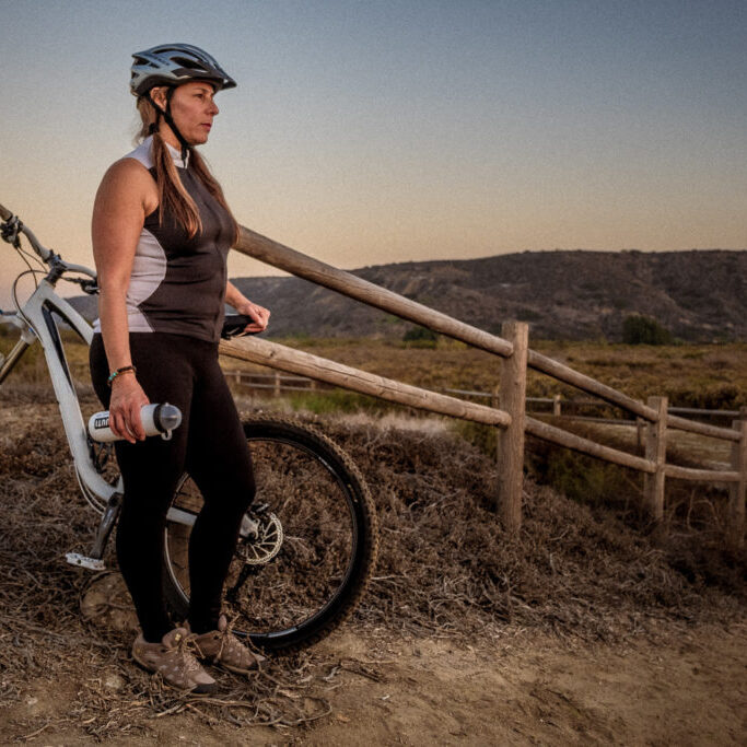 Woman taking a break to watch the sunset after a mountain bike ride through Border Field State Park